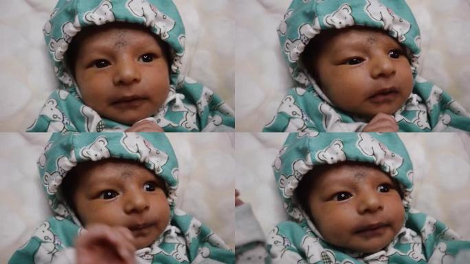 新生婴儿环顾四周。美丽的新生男婴特写镜头 (20天大)。裹着暖和衣服的孩子微笑着抬头。
