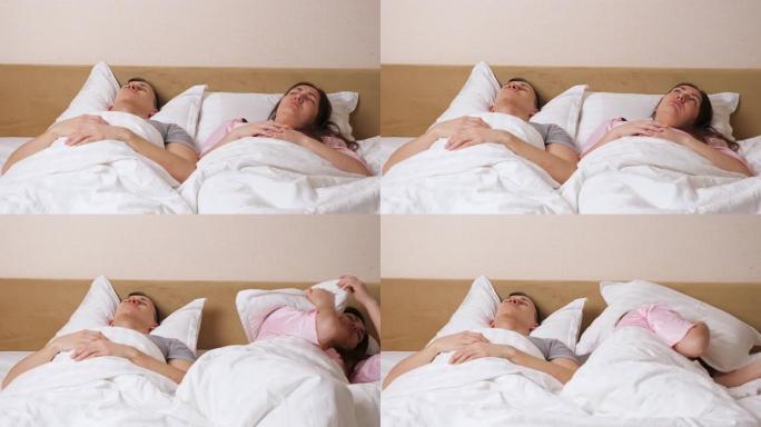 女人躺在打鼾的男人附近，用枕头遮住耳朵