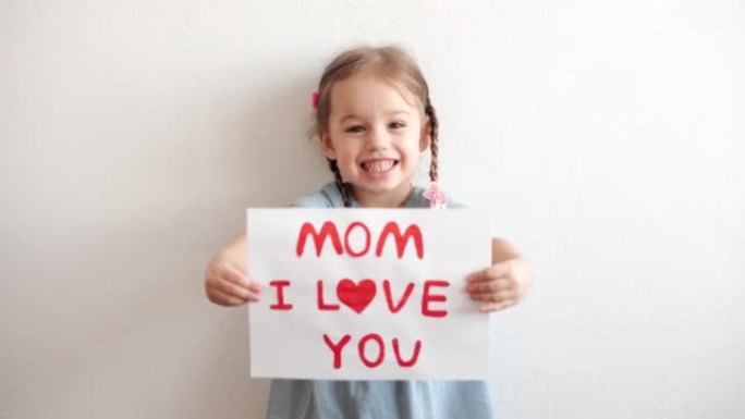 关闭可爱的小学龄前高加索女孩3-4年拿着白色床单的爱的宣言妈妈。小女儿在爱中微笑，用手显示心脏符号。