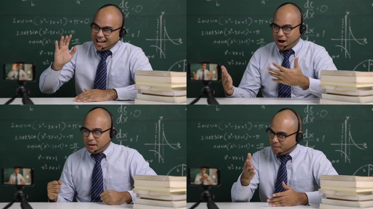 印度青年教师男子坐着戴着耳机教学智能手机在线视频会议直播。亚洲教师在线教授数学课网络研讨会，供学生学