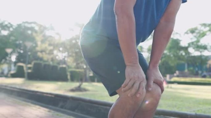 近距离射击老人在公园做膝盖弯曲热身，关节韧带骨问题，踝关节扭伤运动损伤预防
