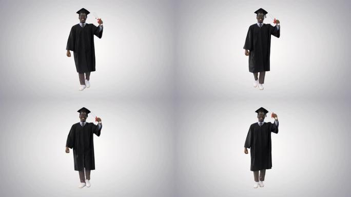 快乐的非洲裔美国男学生穿着毕业长袍带着文凭走路，在渐变背景上对着相机说话
