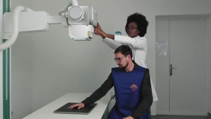 男人手的x光。非裔美国医生制作现代手x光。女技师调整医疗柜中的x光机。扫描骨折和四肢骨折。现代医院