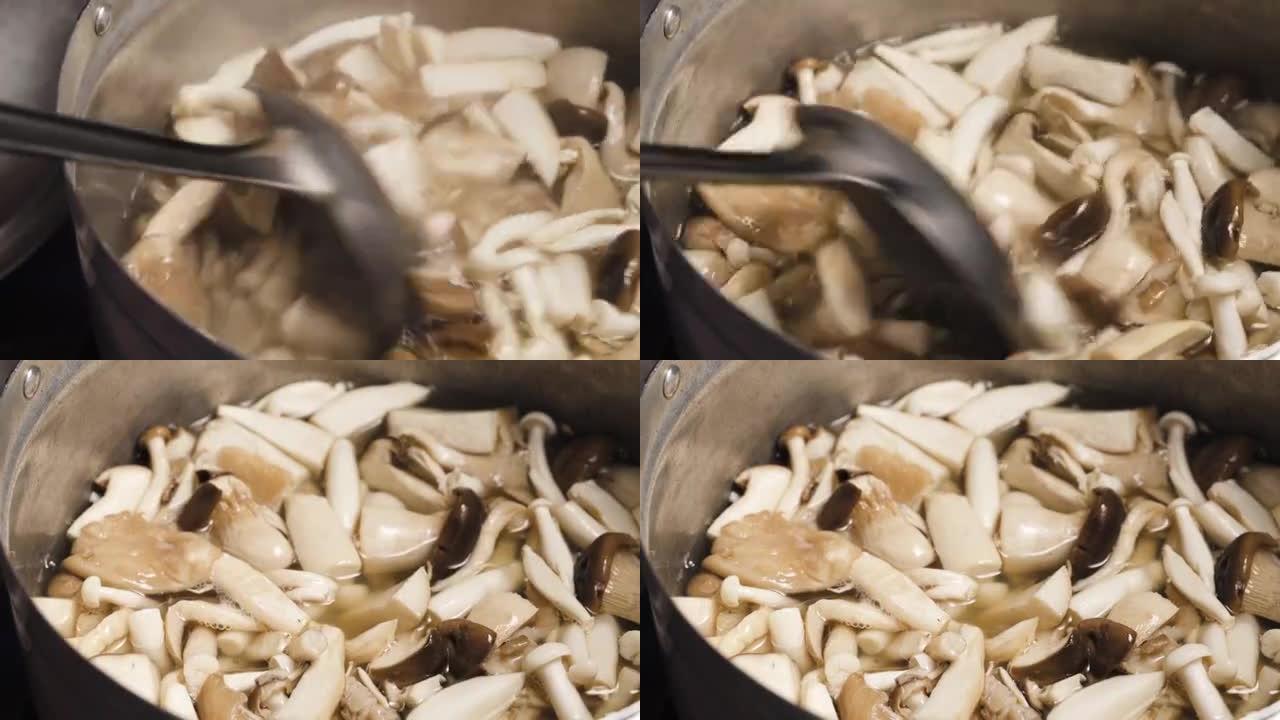 Tom Yum制作泰国传统食物。有人在一壶沸水中搅拌蘑菇。王蚝、凤凰菇、肺蚝。锅。
