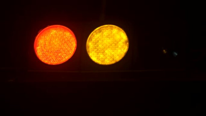 交通信号灯在晚上从红色切换到绿色。垂直悬挂交通灯