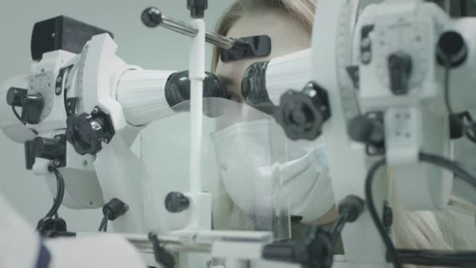女孩病人在眼科医生的办公室检查视力。治愈眼睛，恢复视力。一种用于检查视力的医疗设备。医生负责病人的眼