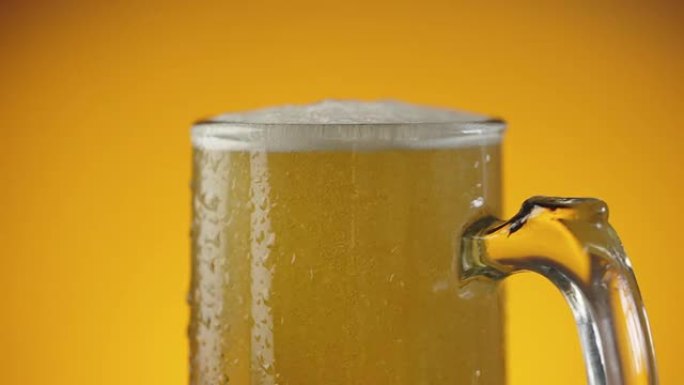 将啤酒喷射到湿的啤酒杯中，并带有大量气泡和泡沫