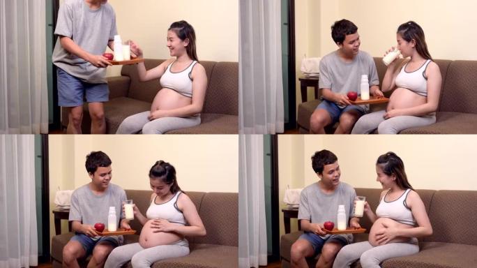 亚洲孕妇和丈夫呆在家里。妇女喝牛奶是为了怀孕的健康和健康。