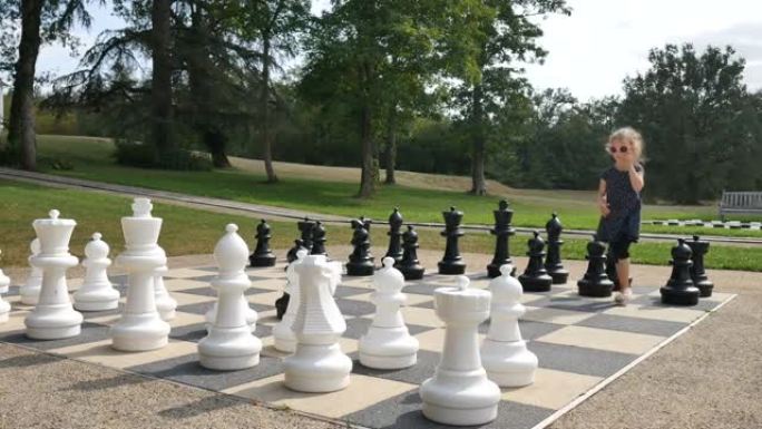 小女孩正在公园外面下棋。活跃的孩子，快乐的童年概念