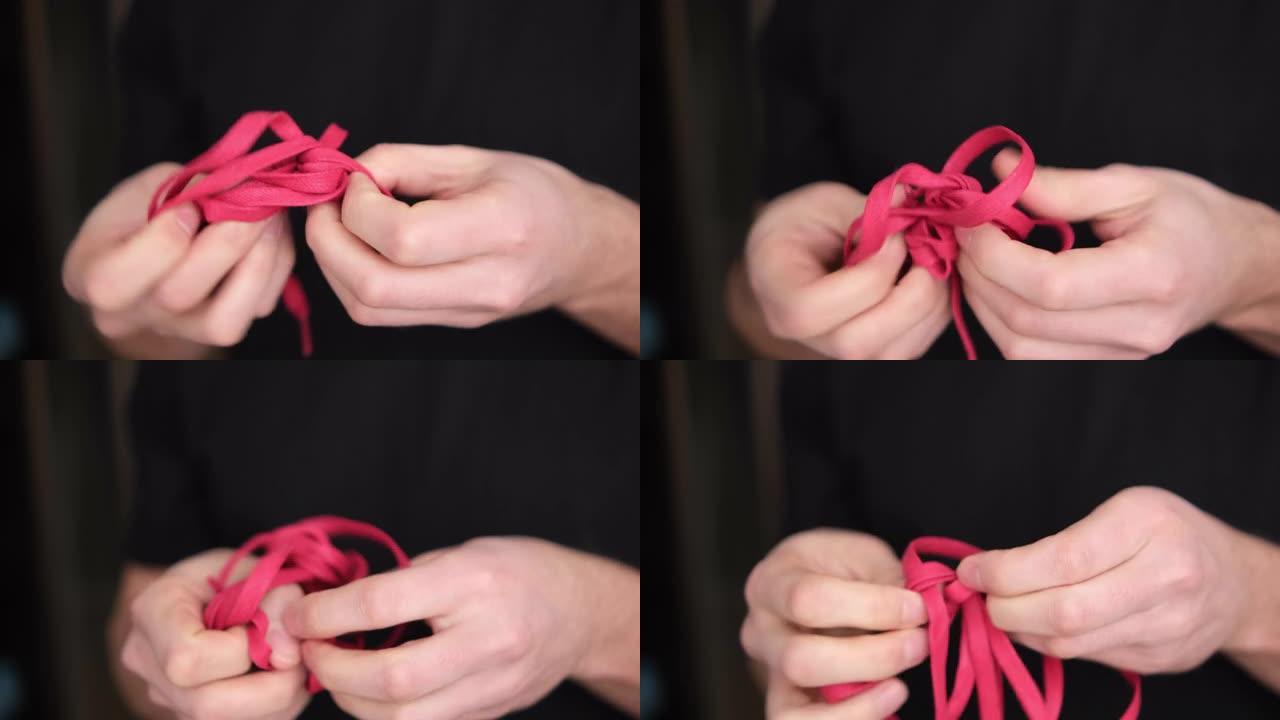 一个人解开一条红色的绳子，在模糊的背景上特写。背景是黑暗的。4K