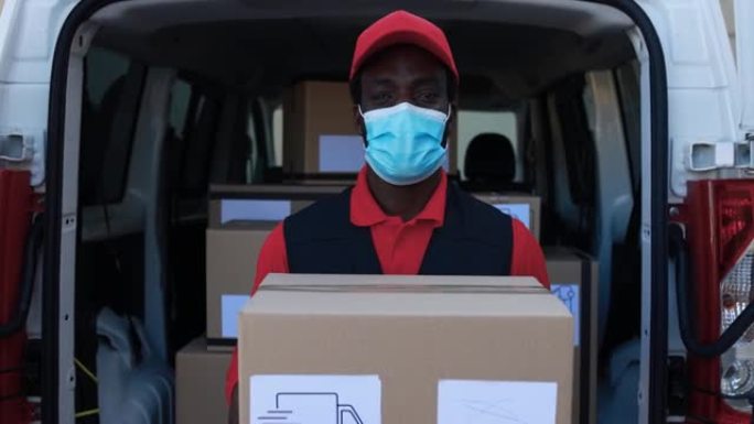 非洲男子快递员用卡车运送包裹，同时佩戴安全面罩以防止冠状病毒