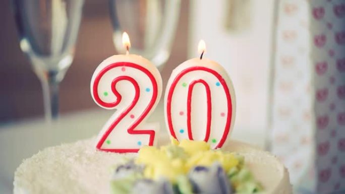 生日蜡烛作为20号20在桌上的甜蛋糕上，20岁生日