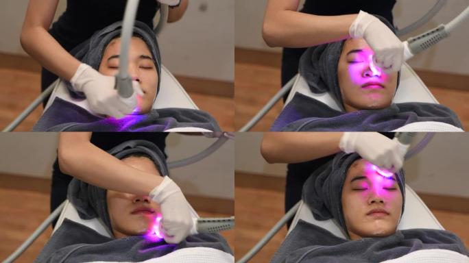 美容师使用激光疗法进行面部皮肤嫩肤的特写。美丽健康的女人脸在水疗沙龙里换肤。