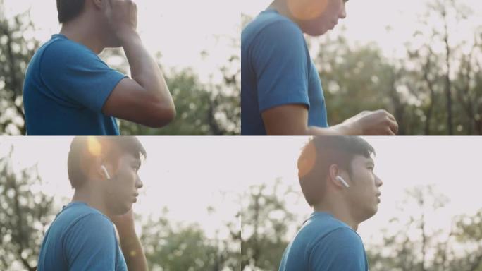 亚洲男子在公园户外跑步时使用无线耳机。积极的生活方式概念。