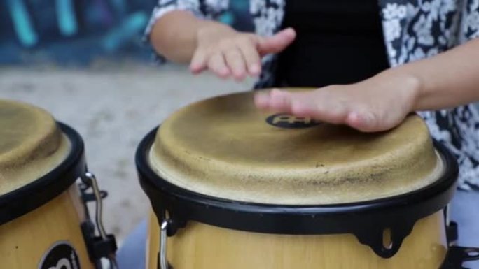 女性打击乐手演奏tummadora鼓。她双手的特写。