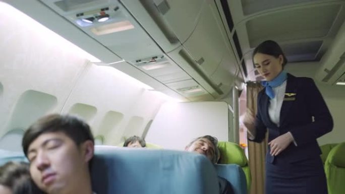 乘务员在头等舱飞机上睡觉时步行并关灯。所有乘客在夜间旅行时感到尝试和困倦。旅游和度假概念