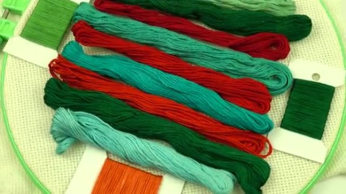 红色和绿色调的绣花线排列在带有帆布的绣花环上