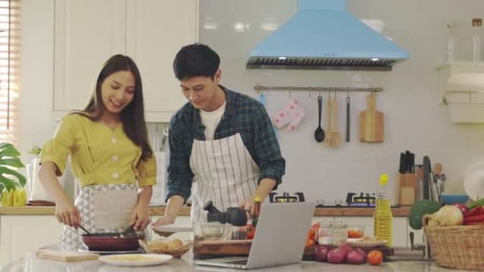 年轻的已婚夫妇正在家里浪漫的气氛中帮忙做饭。情侣们在厨房里通过互相帮助做早餐来表达爱意。