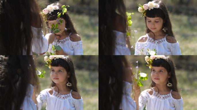 小高加索学龄前女孩的特写肖像，长长的棕色头发和蓝色的眼睛在花环上看着她的姐姐在自然背景上收集花束。4