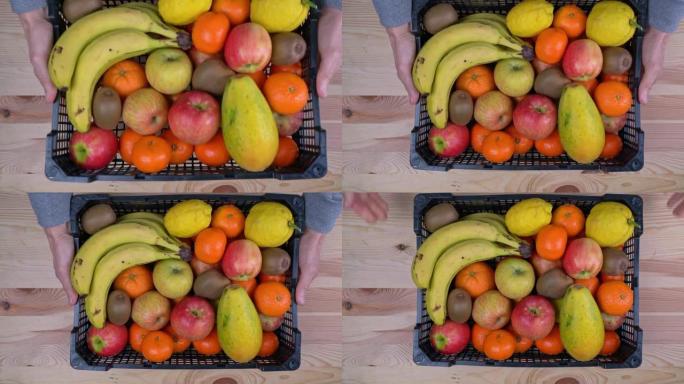 在大流行期间，一名男子以热带水果的形式在盒子里捐赠了一笔捐款。在木制背景上，俯视图。
