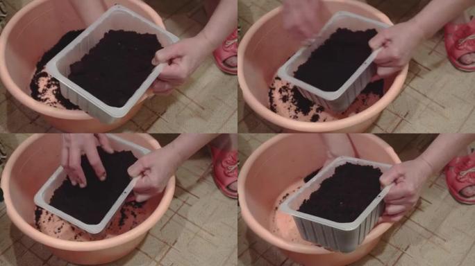 妇女将黑土倒入锅中种植种子