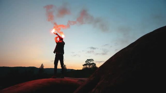 一名男子站在悬崖边上，夜里挥舞着两枚照明弹。在山里生存。在山里徒步旅行。4K。