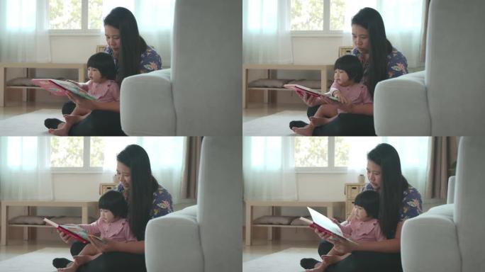 可爱的亚洲蹒跚学步的小女孩和她的妈妈在家里看漫画书，好奇和有趣。