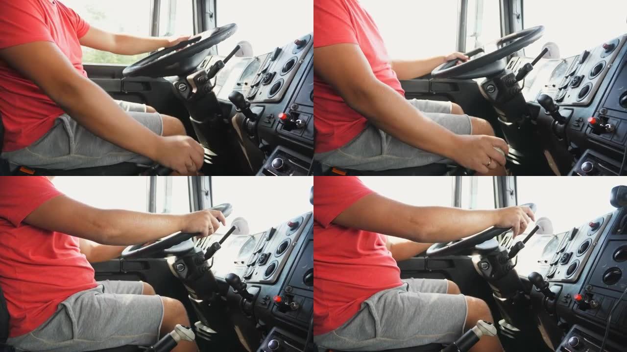 男性臂在驾驶汽车时在手动变速器中换挡。卡车司机的手握着卡车的大方向盘。卡车司机在乡间小路开车到目的地