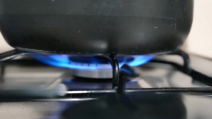 用开水在平底锅下的炉子上燃烧气体。在家做饭。