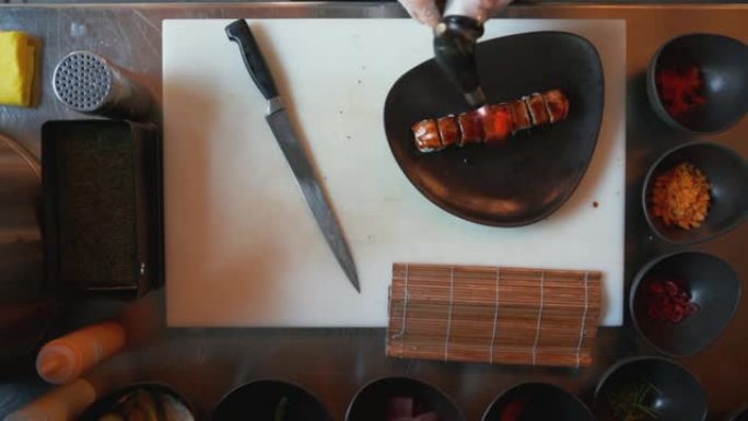 专业厨师用热风枪加热寿司的俯视图。用热风枪在寿司上烹饪鲑鱼的俯视图