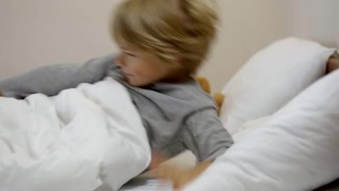 快乐可爱的男孩在卧室醒来的侧视图。快乐微笑的高加索孩子伸展身体，坐在床上。在家和童年的觉醒