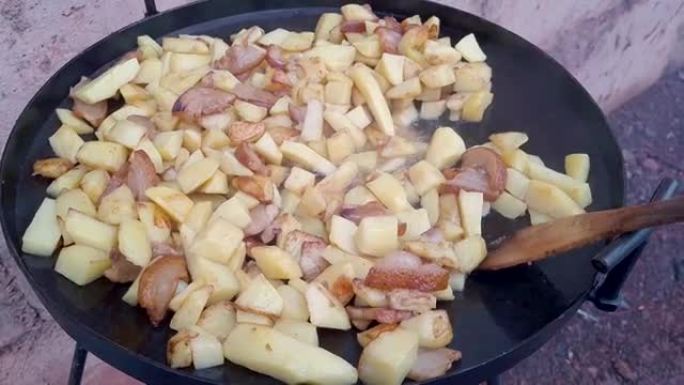 土豆在巨大的黑色圆锅上用脂肪油炸，用中耕者圆盘制成。