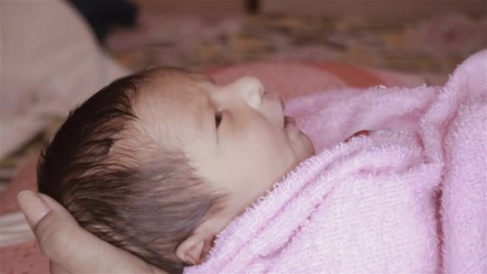 美丽的新生男婴特写镜头 (6天大) 躺在产前医院的妈妈腿上。裹着婴儿毯的孩子 (保暖的衣服) 微笑着