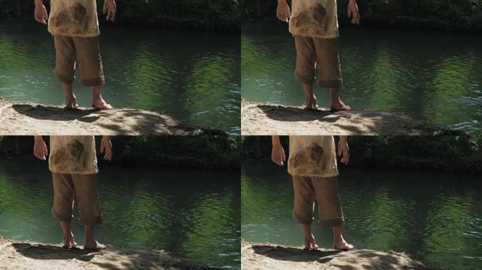 两个男孩穿着脏衣服，光着脚在河岸上闲逛。