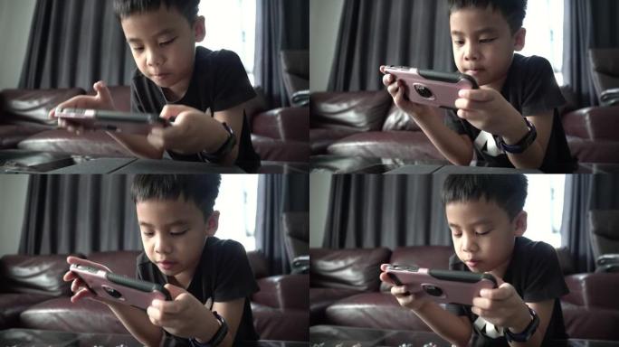 亚洲男孩玩智能手机游戏。