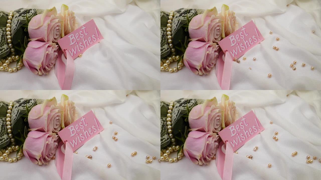 粉红色的珍珠珠子落在白色的丝绸上，一束玫瑰花和一张卡片上的祝福
