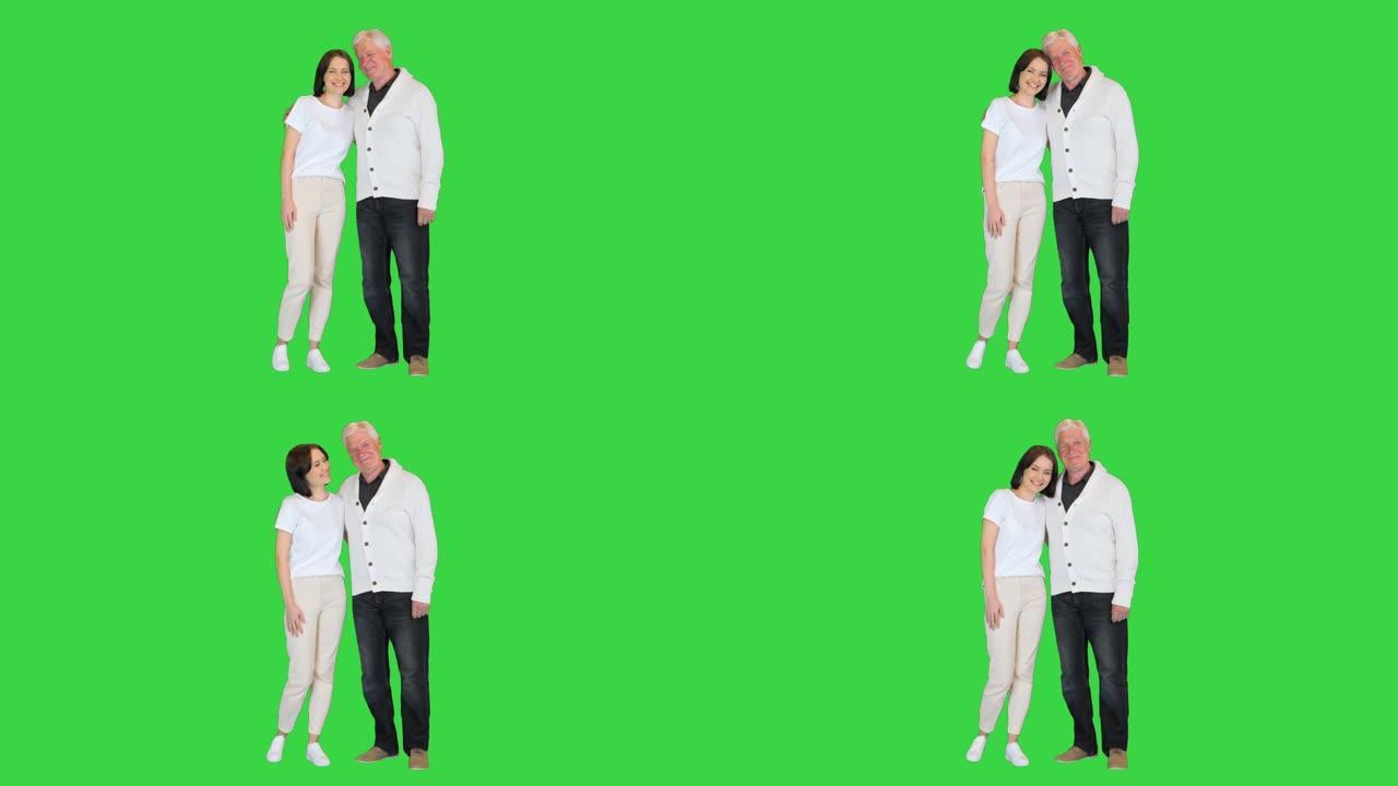 成年孙女和80年代的祖父在绿色屏幕上的相机上微笑，色度键