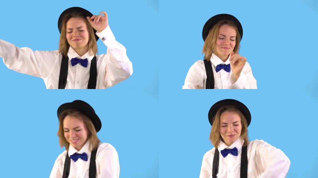 穿着黑色帽子，白色衬衫，领结和吊带的美女在蓝色背景上跳舞。