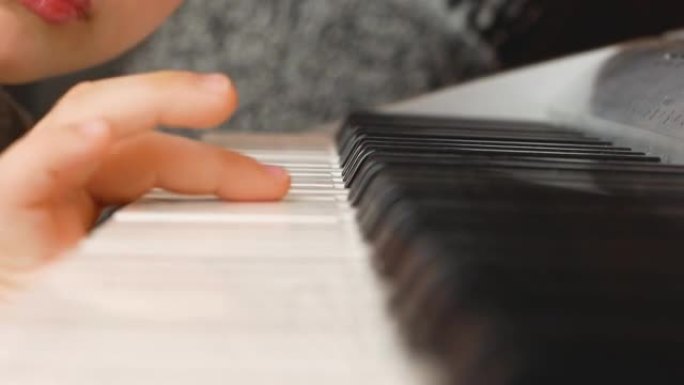 特写疲倦的高加索学龄前儿童将头躺在钢琴上。教孩子们弹钢琴。音乐能力的发展。选择性聚焦，浅景深