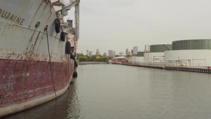 揭示了停泊在港口的旧生锈货船后面的纽约市港口和红钩谷物码头