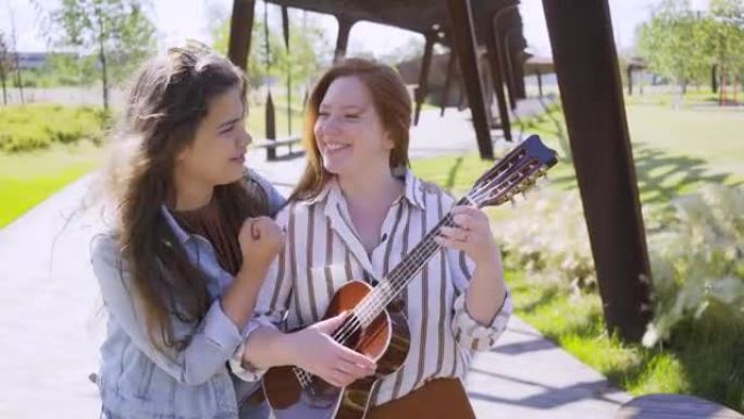 女人拥抱朋友在当代城市公园玩尤克里里琴