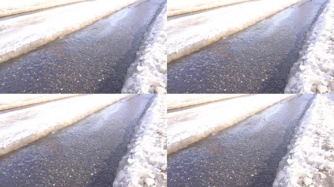 雪地上的车辙在春天的阳光下融化，露出了柏油路面