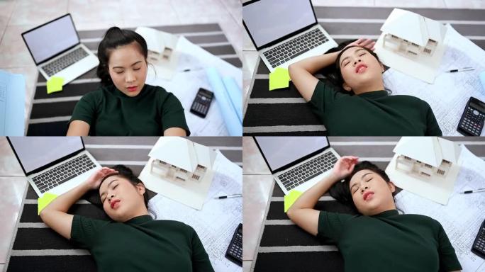 亚洲女建筑师累了，躺在家里办公室的地板上，在家工作。建筑师和工程师概念。