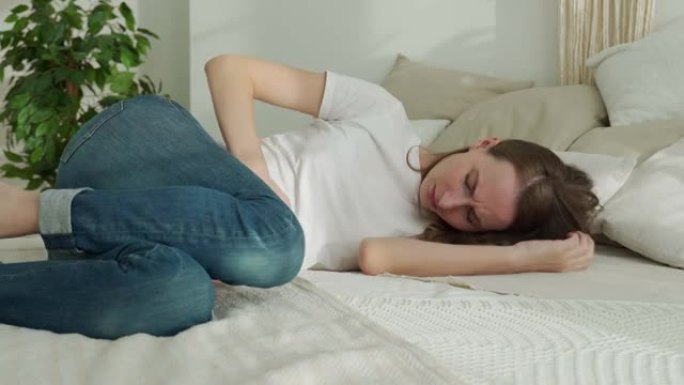 年轻女子患有胃痛，感到腹痛或抽筋，躺在床上。经期月经