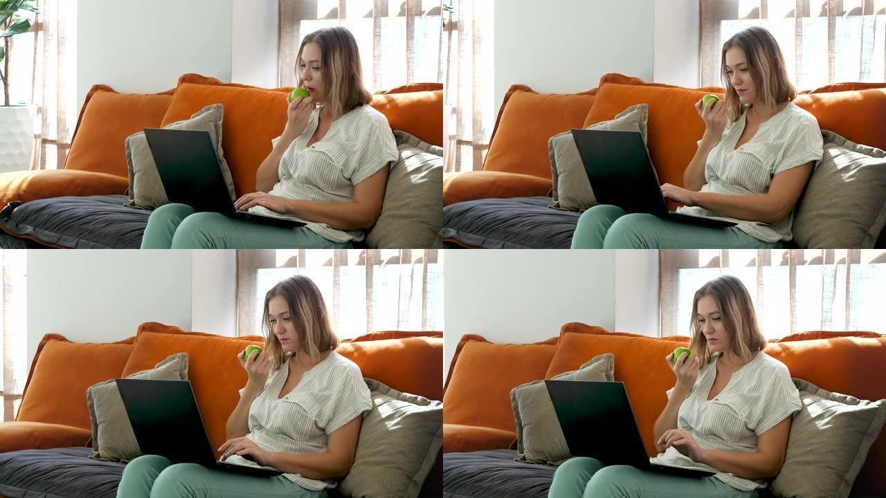 可爱创意女博主在笔记本电脑上打字文字在家吃青苹果