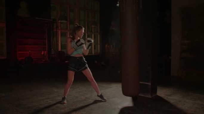 Cool female fighter in boxing gloves trains in the