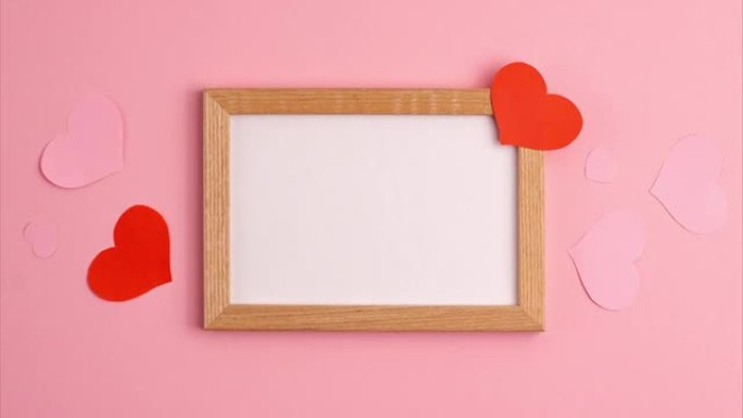 红色和粉红色纸心的停止运动动画在粉红色背景上及其附近的木制框架情人节爱情关系浪漫周年婚礼节日概念平躺