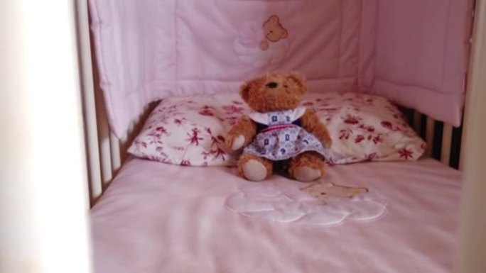 在白色儿童床上关闭一个软熊玩具。婴儿床