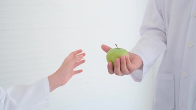 年轻的高加索科学家女孩在学习前将青苹果送给她的亚洲老师，以表示对老师的尊重