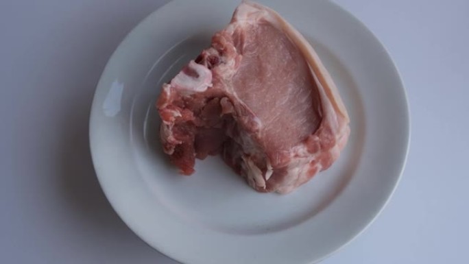 白色盘子上的一块肉 (猪排)。烧烤用新鲜猪肉